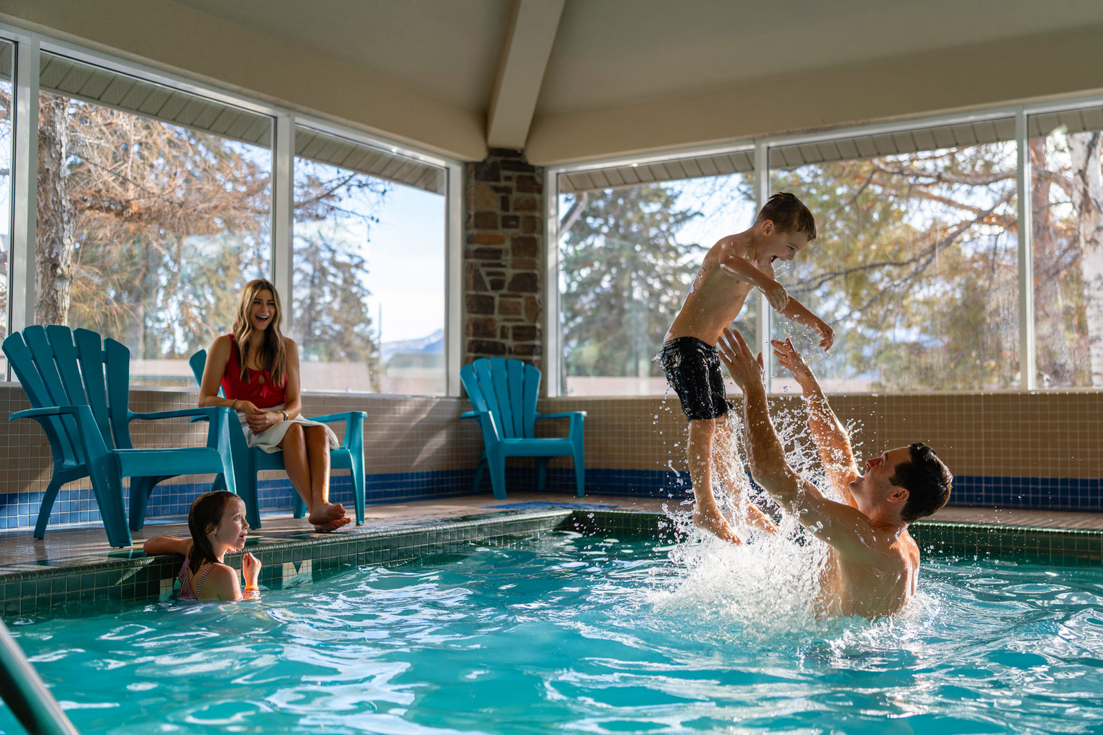 family in the pool with the father throwing the son into the air